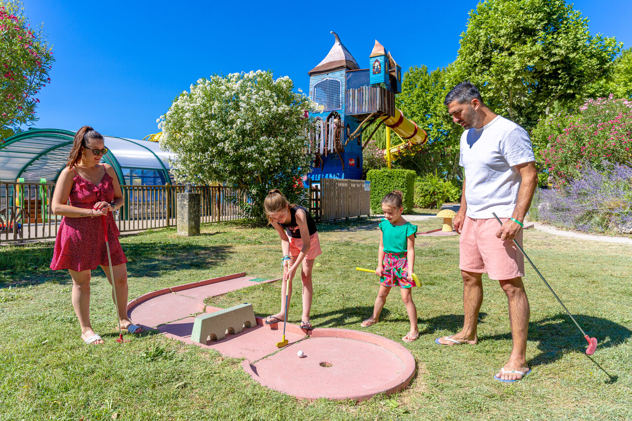 Famille jouant au mini-golf avec aire de jeux et piscine au camping CAPFUN Jantou � LE THOR (84).