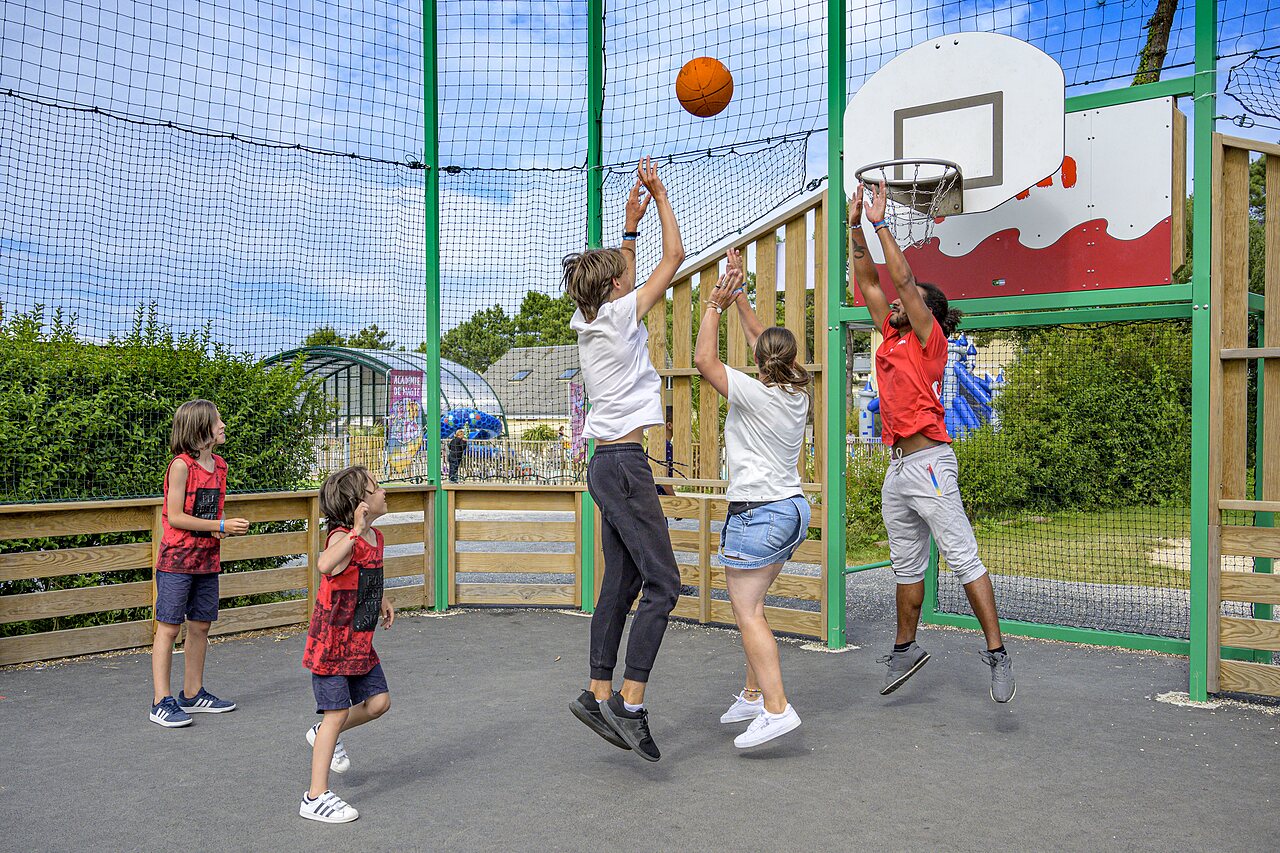 Famille et animateur jouent au basketball sur terrain multisport au CAPFUN Joncal.