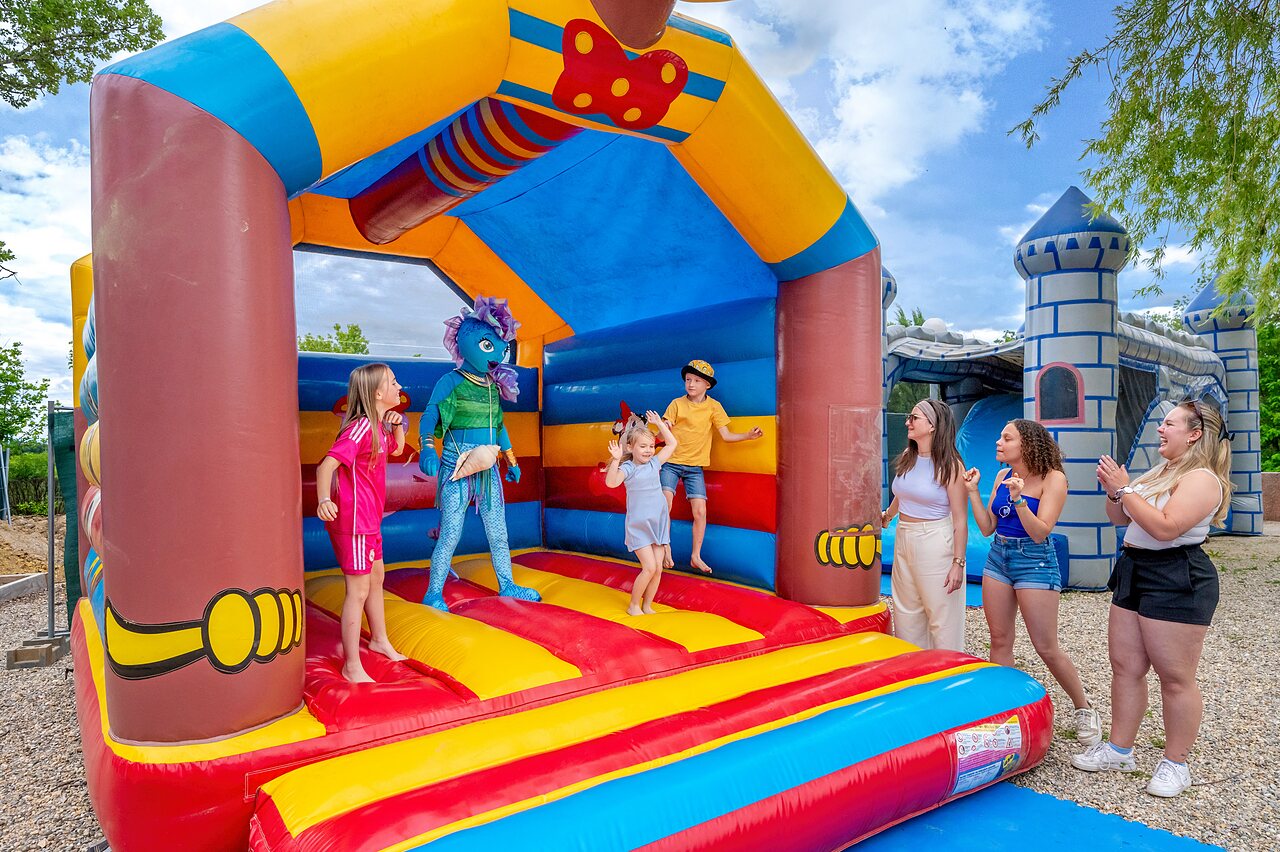 Enfants et mascotte sur ch�teau gonflable color� au camping VAGUES OCEANES Labeiller.