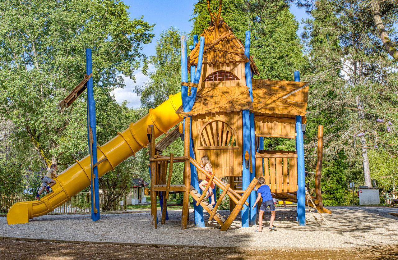 Aire de jeux en bois avec toboggan jaune pour enfants au camping CLICOCHIC Lac de Miel � Beynat (19).