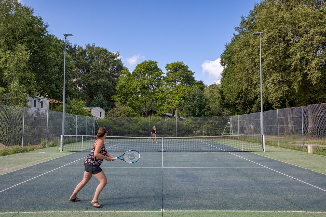 Court de tennis ext�rieur avec deux femmes jouant au camping CLICOCHIC Lac de Miel � Beynat (19).