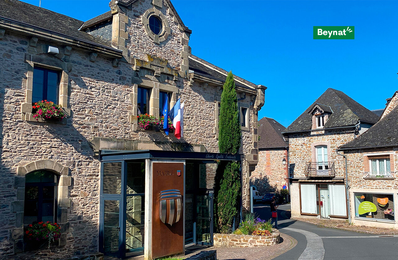 Mairie de Beynat, b�timent en pierre avec drapeaux fran�ais et fleurs en Corr�ze.