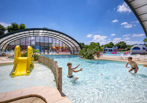 Piscine extérieure, toboggan jaune et enfants au camping CAPFUN Lac de Ribou.