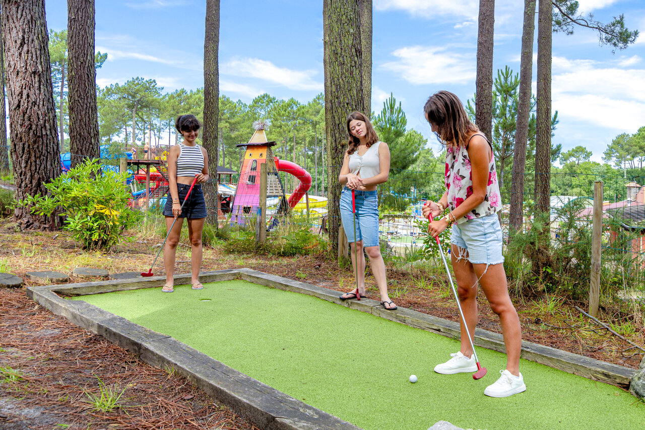 Mini-golf avec jeunes femmes jouant, entour� de pins au camping CAPFUN Landisland � Moliets-et-Maa.