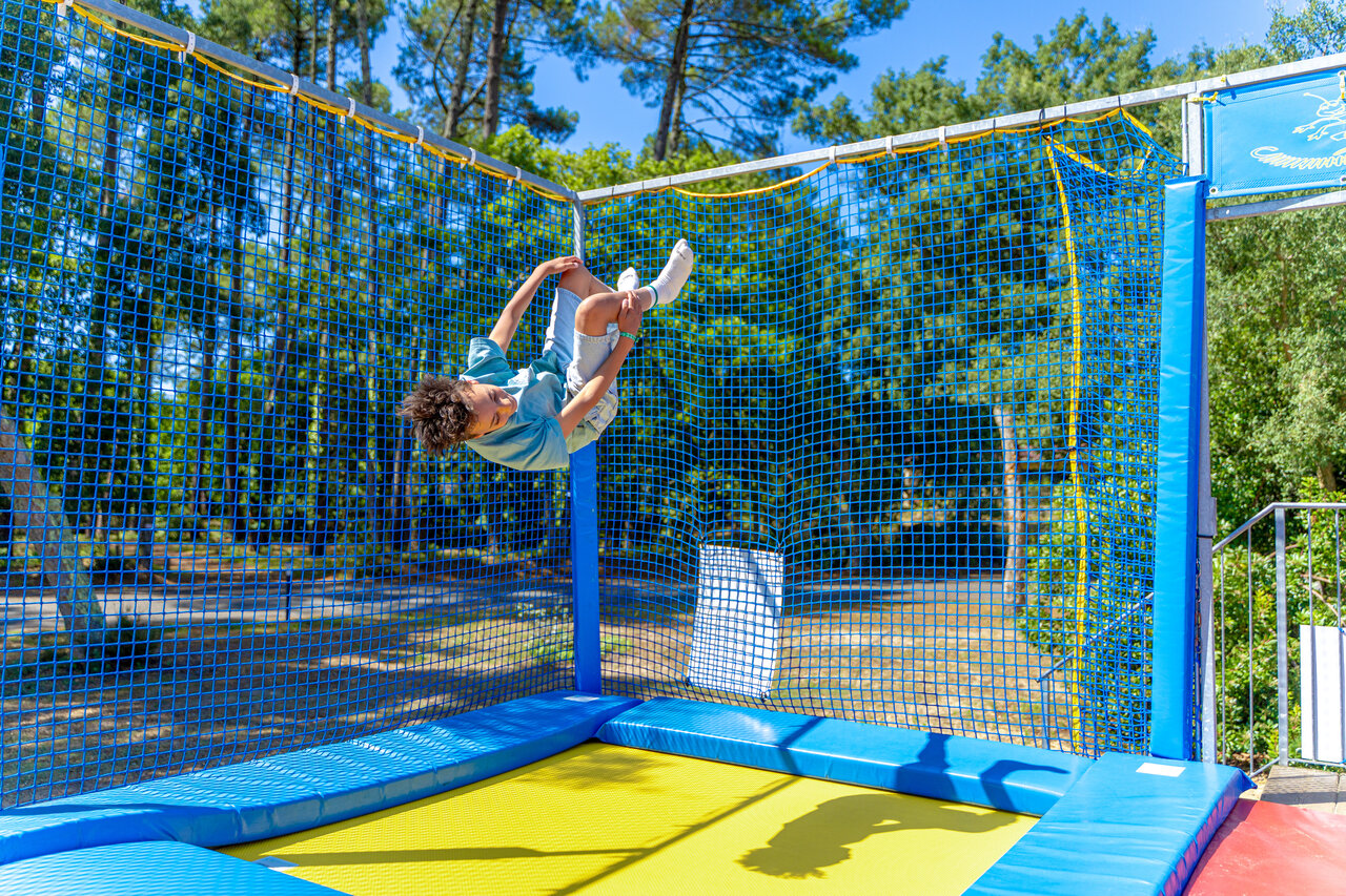 Enfant sautant sur un trampoline s�curis� avec filet au camping CAPFUN Landisland � Moliets-et-Maa (40).