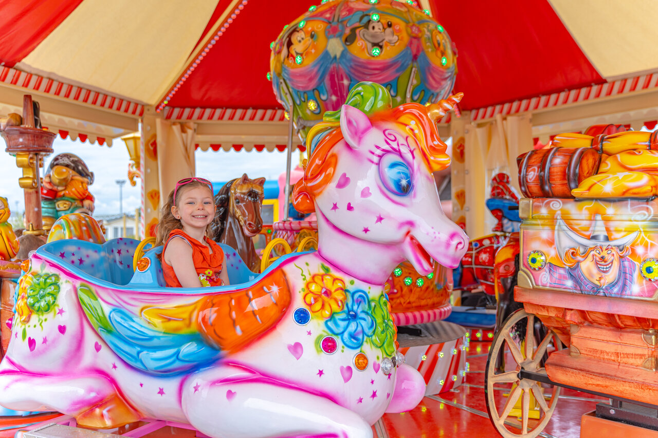 Enfant souriant sur man�ge licorne au camping VAGUES OCEANES Licorne � Dunkerque (59).