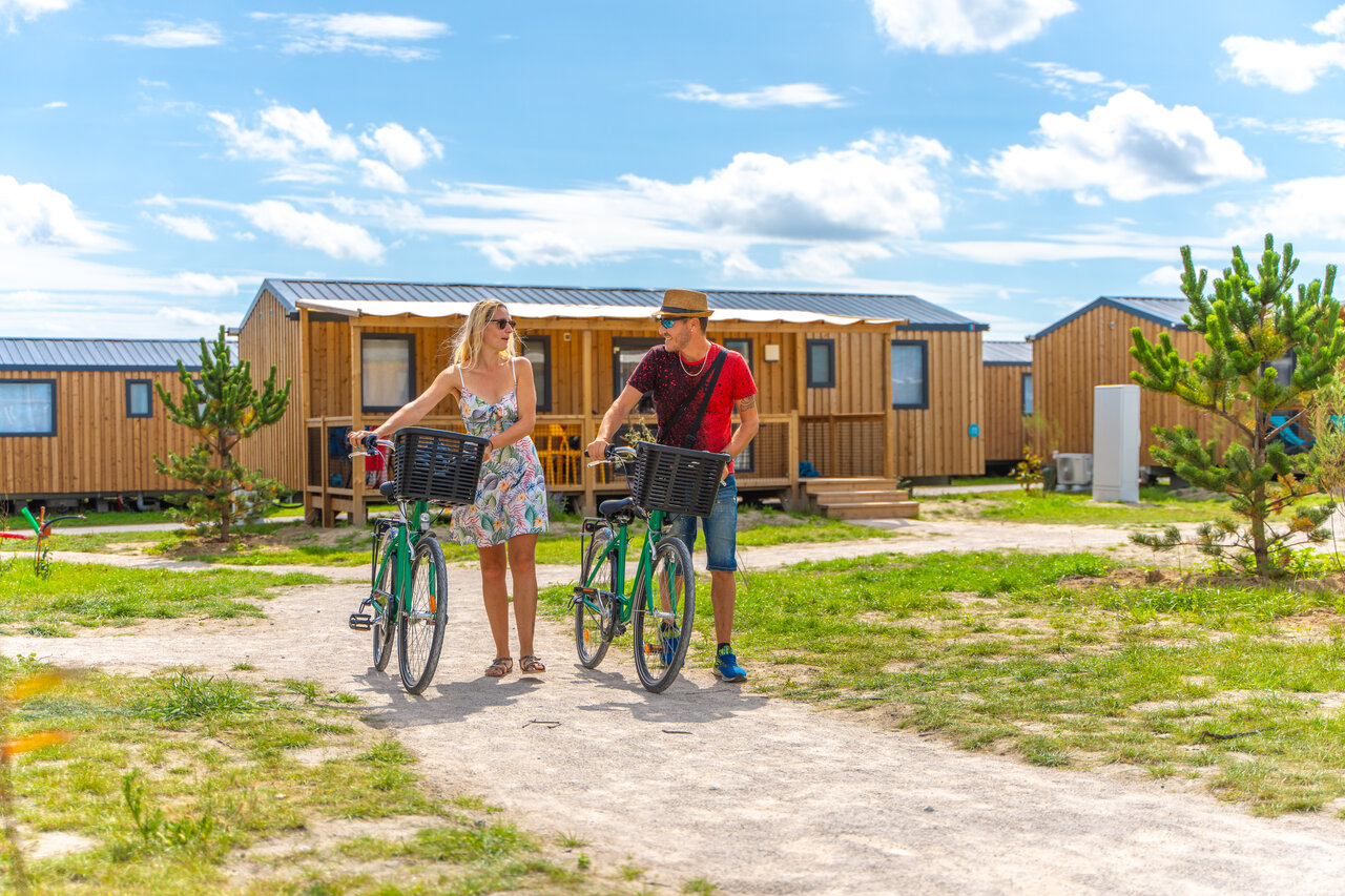 Couple avec v�los devant des mobile-homes modernes au camping VAGUES OCEANES Licorne � Dunkerque (59).