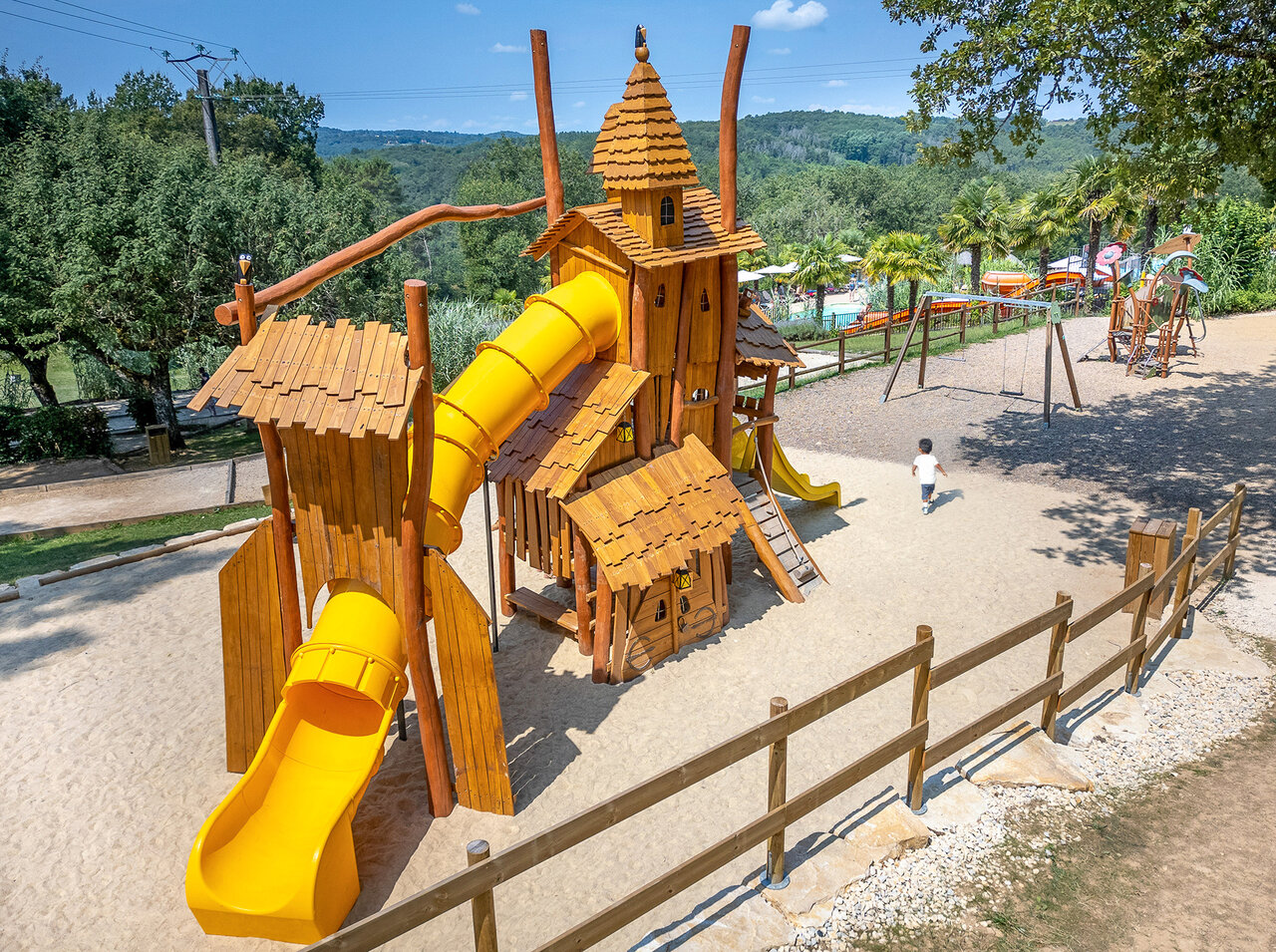 Aire de jeux en bois avec toboggans jaunes pour enfants au camping CLICOCHIC Linotte � Le Bugue (24).