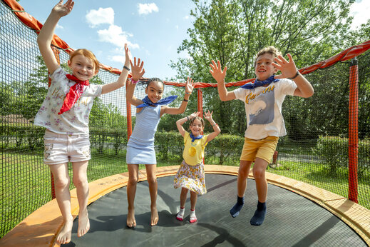Enfants joyeux sautant sur un trampoline sécurisé au camping CLICOCHIC Linotte à Le Bugue (24).