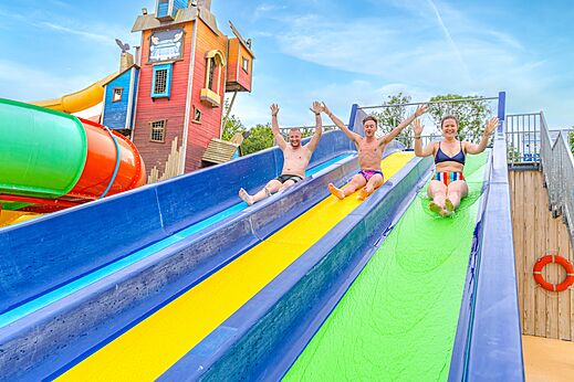 Trois personnes glissant sur des toboggans aquatiques colorés au camping CAPFUN Lodge à SARZEAU (56).