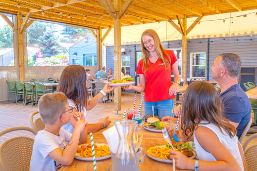 Serveuse CAPFUN servant des repas à une famille au restaurant du camping CAPFUN Loubine à Les Sables d'Olonne (85).