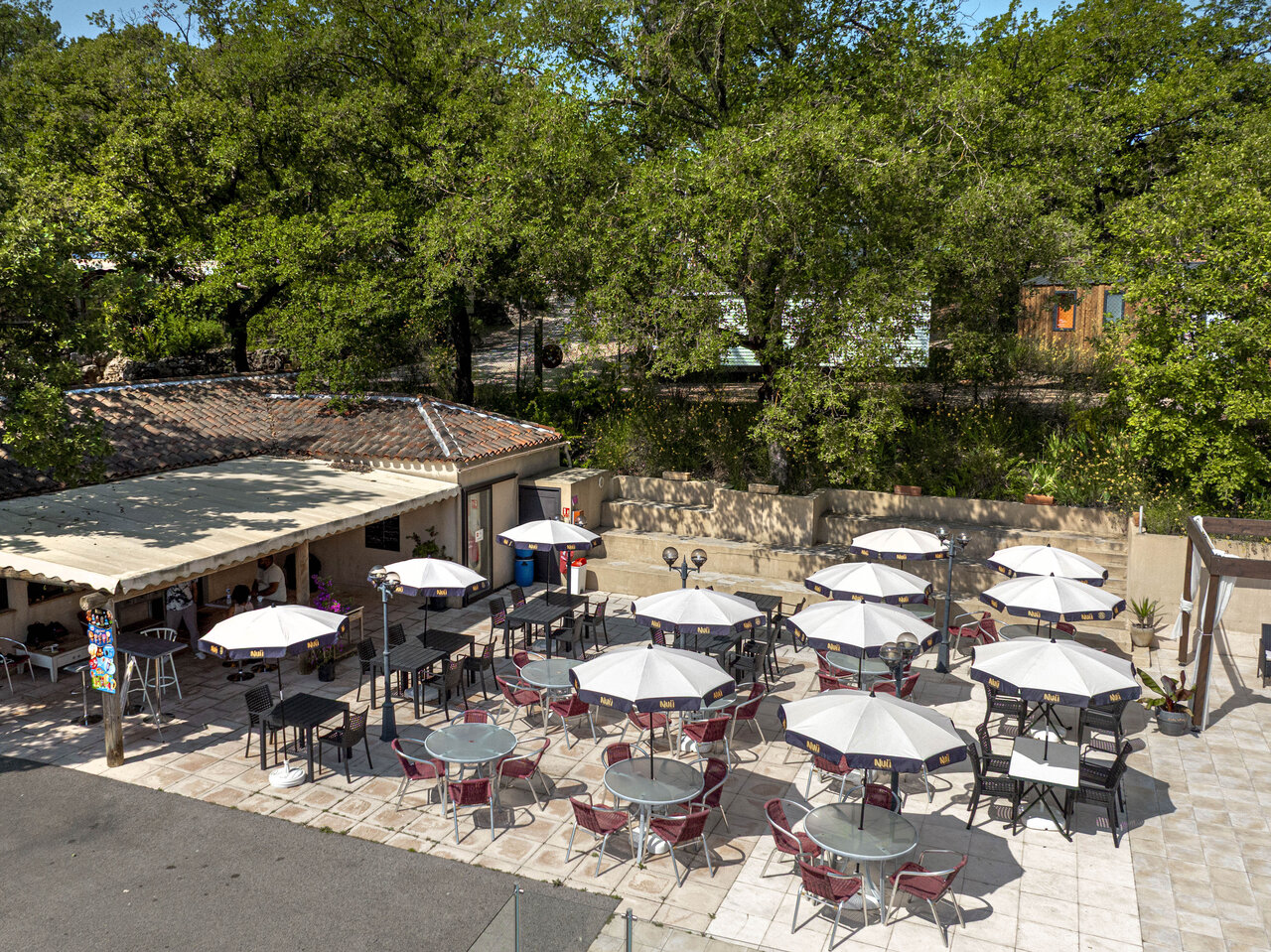 Terrasse de restaurant ext�rieure avec parasols et tables au camping CLICOCHIC Lou Cantaire � FAYENCE (83).