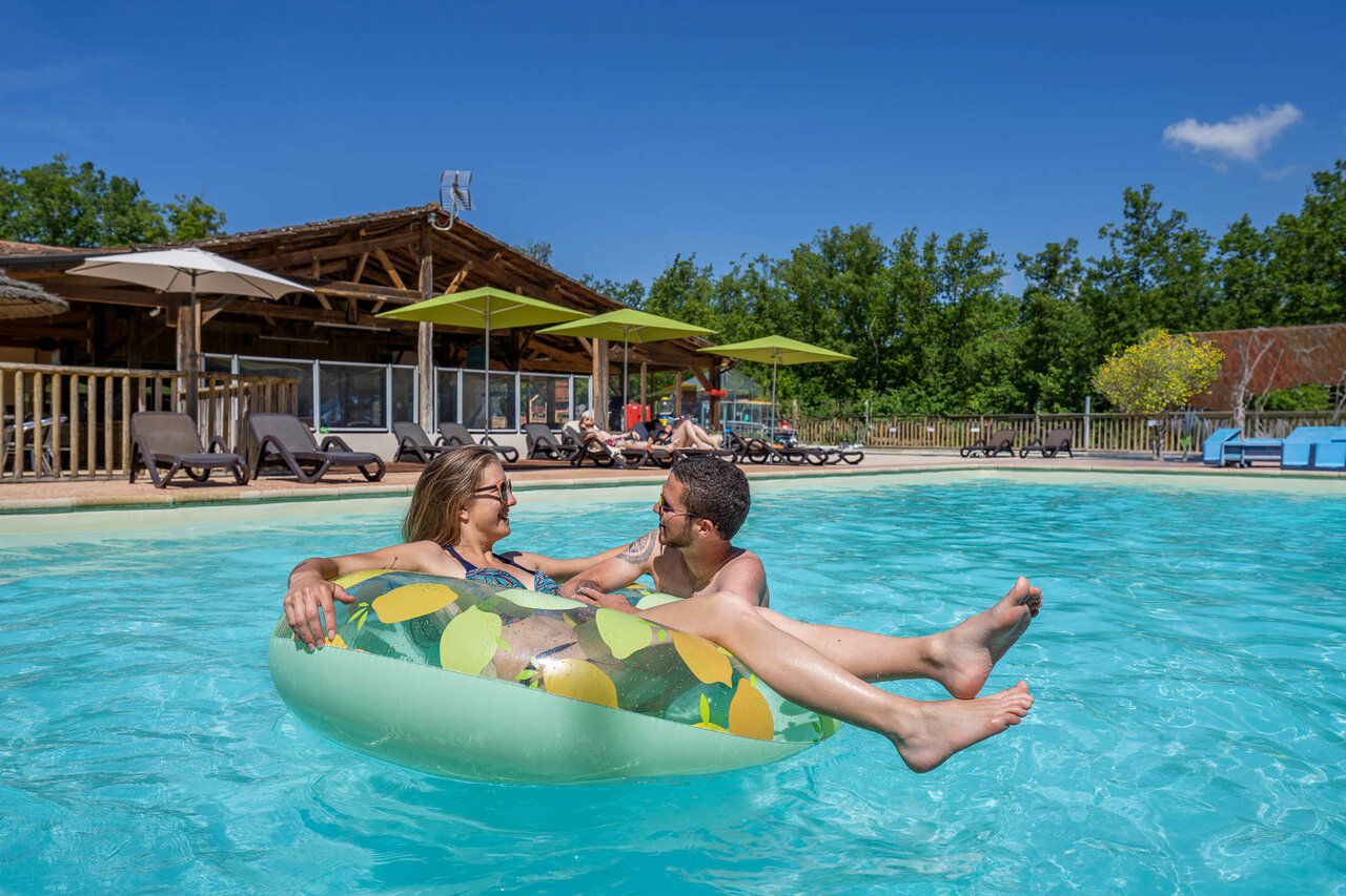 Piscine ext�rieure, couple souriant sur bou�e. Camping CLICOCHIC Lou Castel.