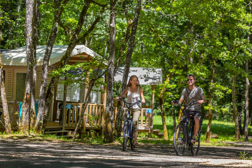 Couple à vélo sur un chemin boisé près de Mobil-homes au camping CLICOCHIC Lou Castel.