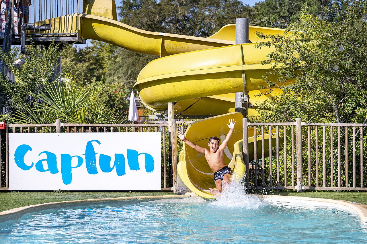 Enfant heureux sur toboggan aquatique jaune, piscine, CAPFUN Lou Puntaou � LEON (40).
