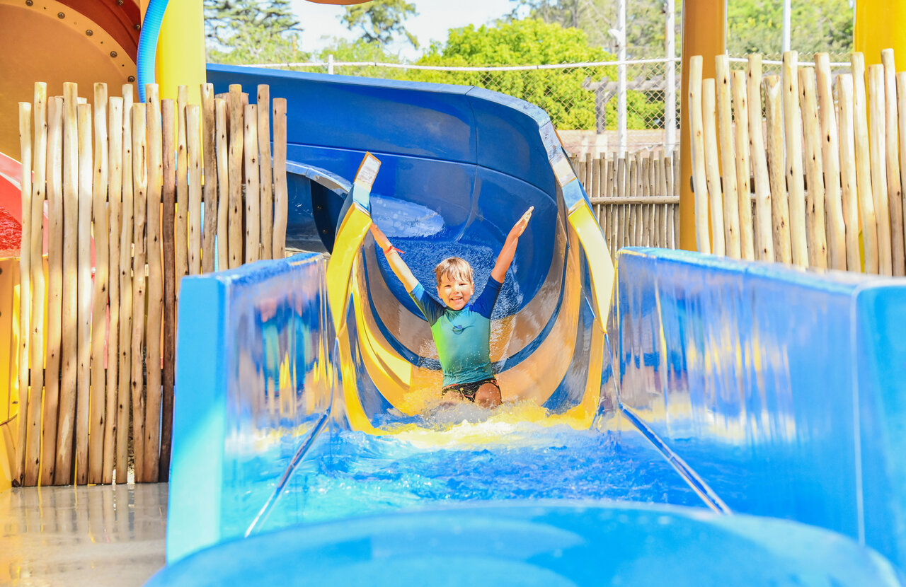 Enfant souriant descendant toboggan aquatique au camping CAPFUN Marina d'Al�ria � Aleria (20).