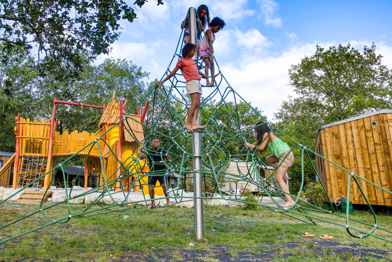 Enfants sur structure d'escalade en corde, aire de jeux, camping CLICOCHIC M�doc Bleu.