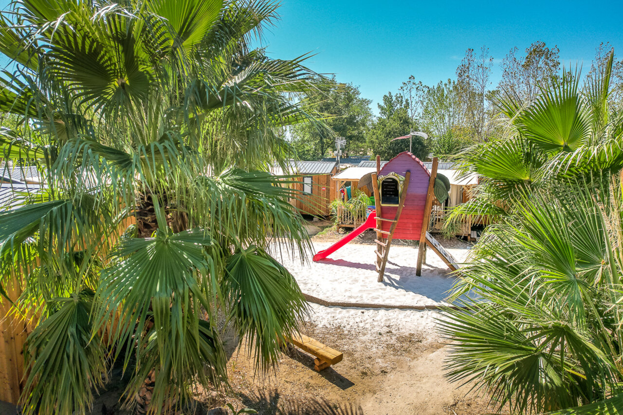 Aire de jeux pour enfants avec cabane rouge et toboggan au camping CAPFUN Mer et Soleil � Cap d'Agde (34).