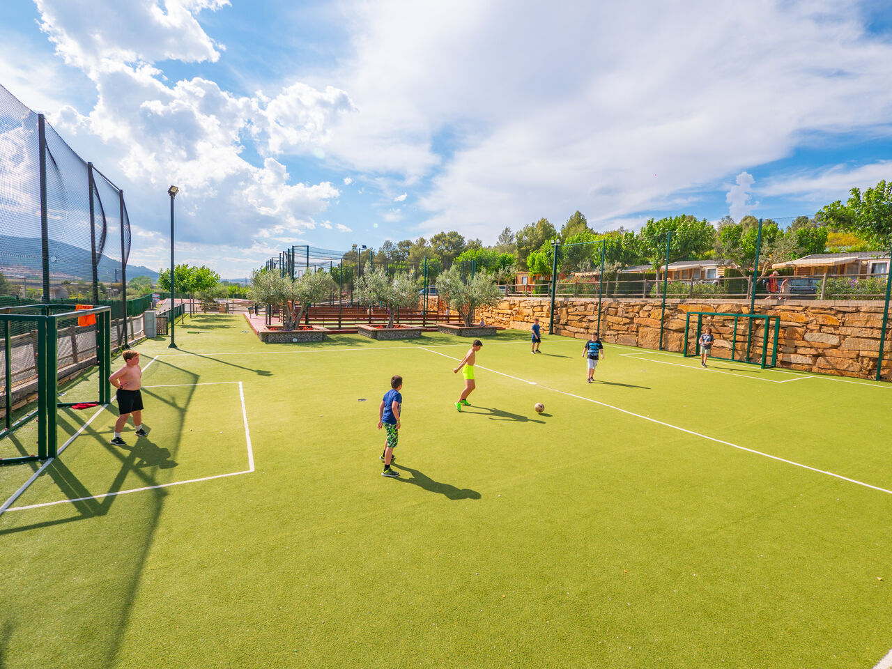Enfants jouant au football sur terrain multisport, Mobil-homes au camping CAPFUN Montblanc Park (43).