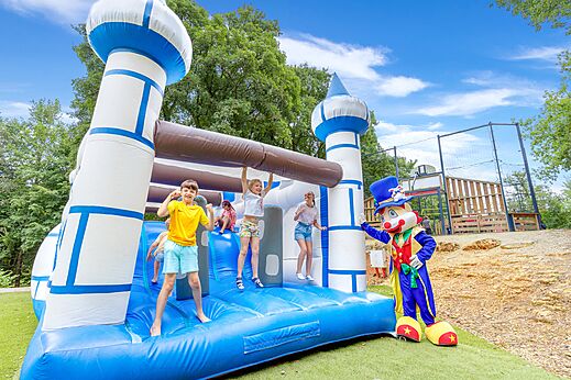 Château gonflable et enfants joyeux avec mascotte au camping CAPFUN Moulinal à BIRON (24)
