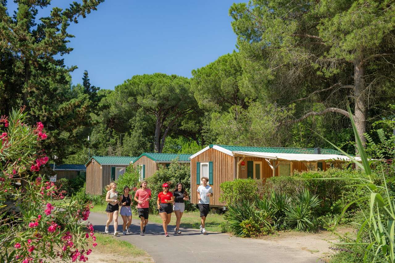 Jeunes joggeurs et mobile homes en bois au camping CAPFUN Or � La Grande Motte (34).