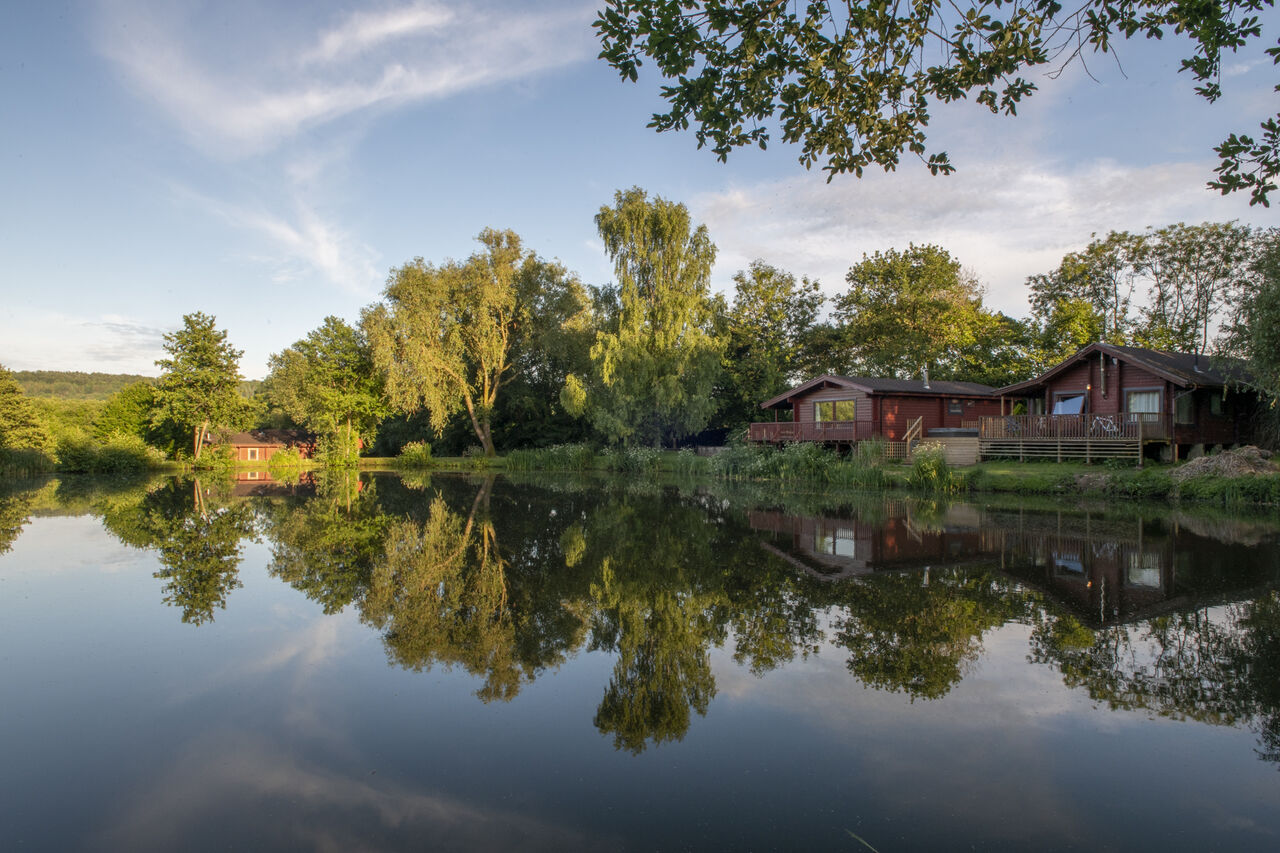 Mobil-homes en bois au bord d'un lac, reflets, camping CAPFUN UK Otter Falls.