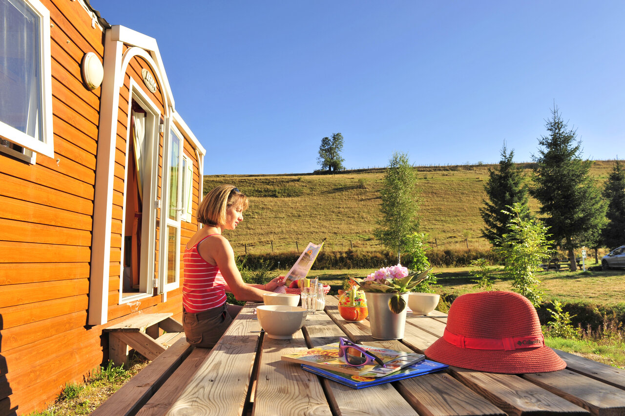 Femme sur terrasse de Mobil-home, vue nature, au camping CAPFUN Oursi�re � Villard de Lans (38).