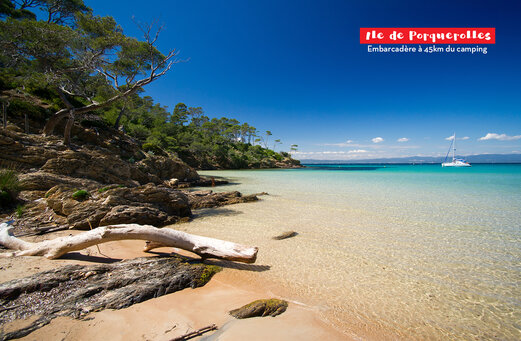 Plage paradisiaque de l'Île de Porquerolles, eaux turquoise, côte rocheuse et voilier.