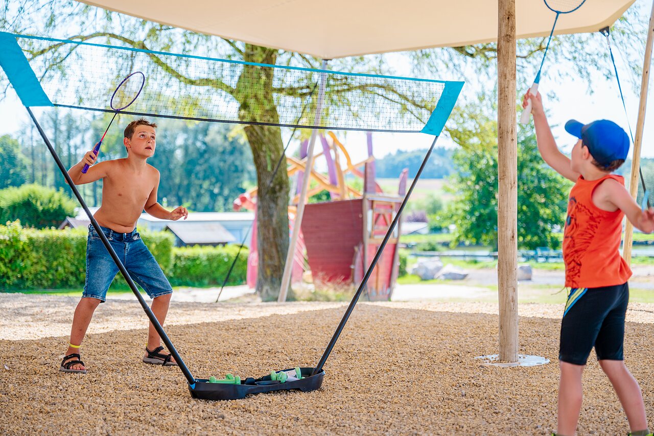 Enfants jouant au badminton sur terrain de gravier au camping CAPFUN Pachy � FOSSES LA VILLE.