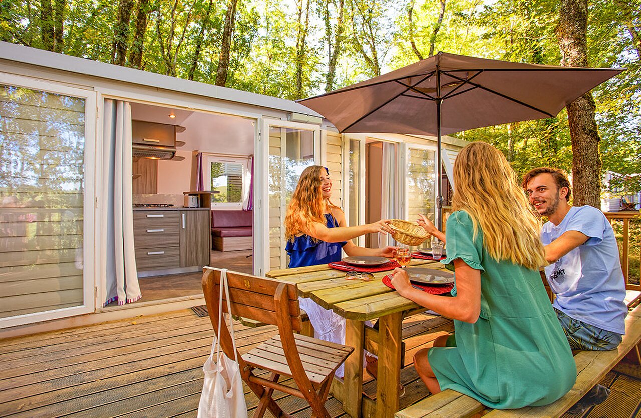 Mobil-home moderne, terrasse en bois, repas en famille au camping VAGUES OCEANES Paille Basse.