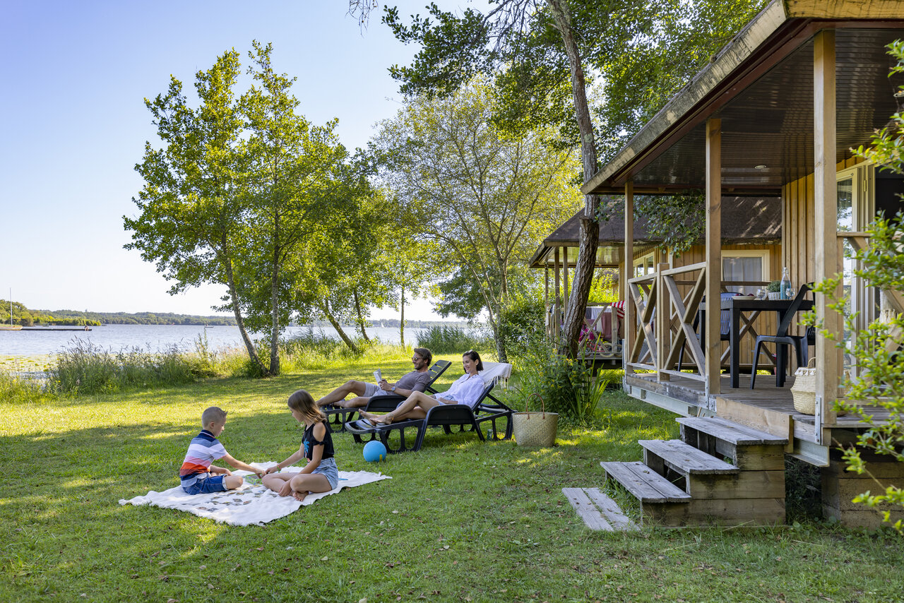 Famille se relaxant devant un Mobil-home au bord du lac, au camping CAPFUN Paillotte � AZUR (40).