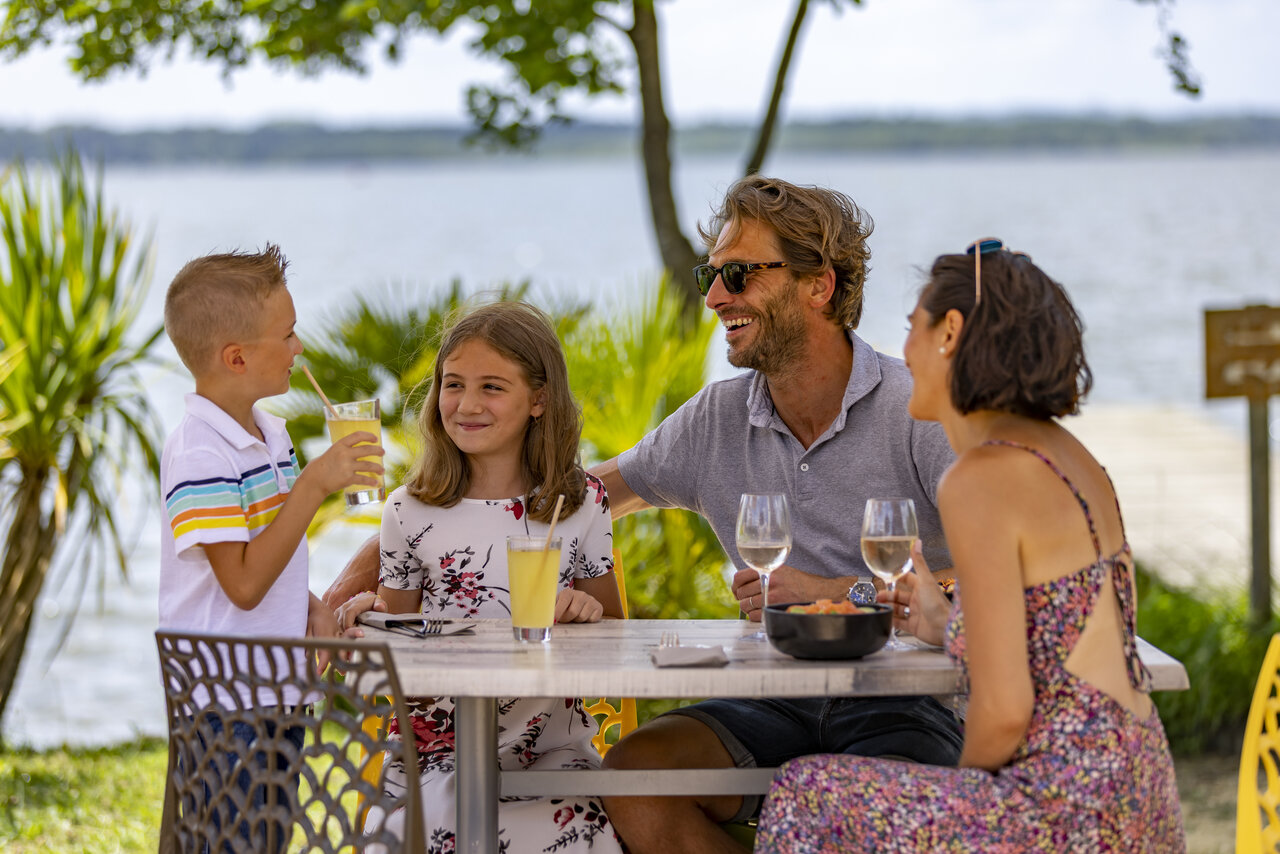 Famille d�jeunant au restaurant en bord de lac, camping CAPFUN Paillotte � AZUR (40).