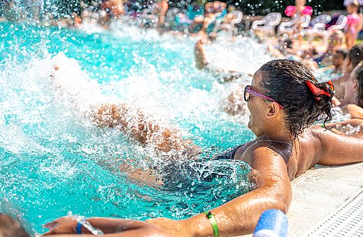 Piscine extérieure avec jets d'eau et baigneurs au camping CAPFUN Palais de Gaufrette (57).