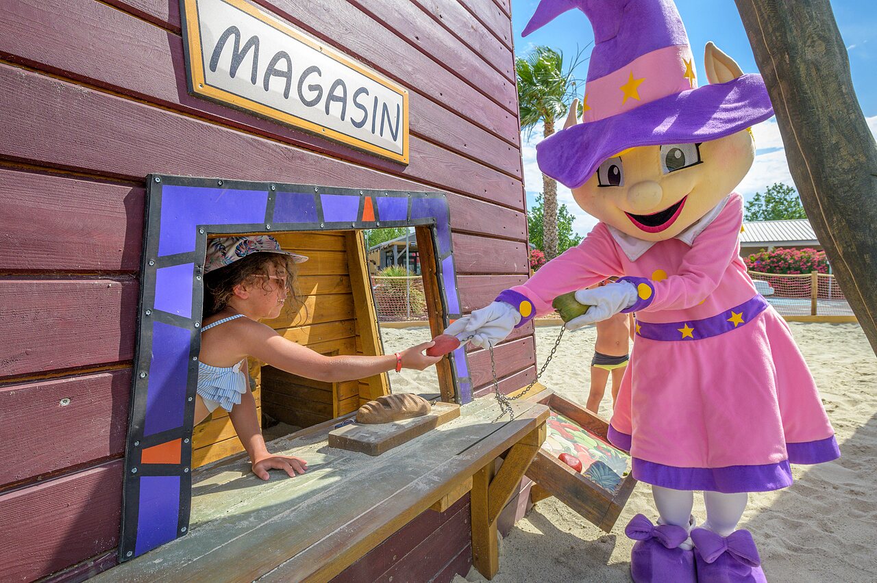Enfant jouant avec la mascotte devant un petit magasin au camping CLICOCHIC Palmira Beach � Vendres-Plage (34).