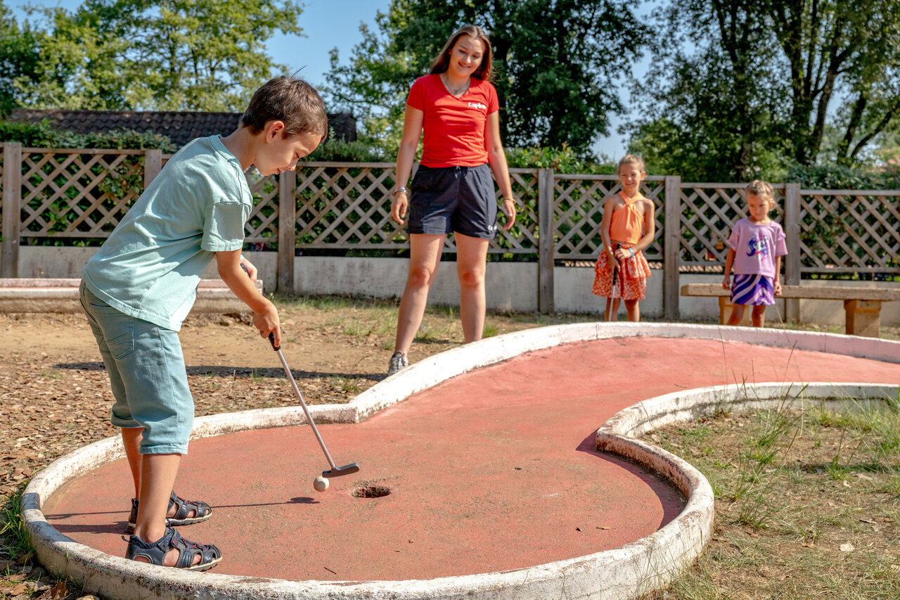 Enfant joue au mini-golf avec animateur au CAPFUN Palombi�re Sarlat (24).