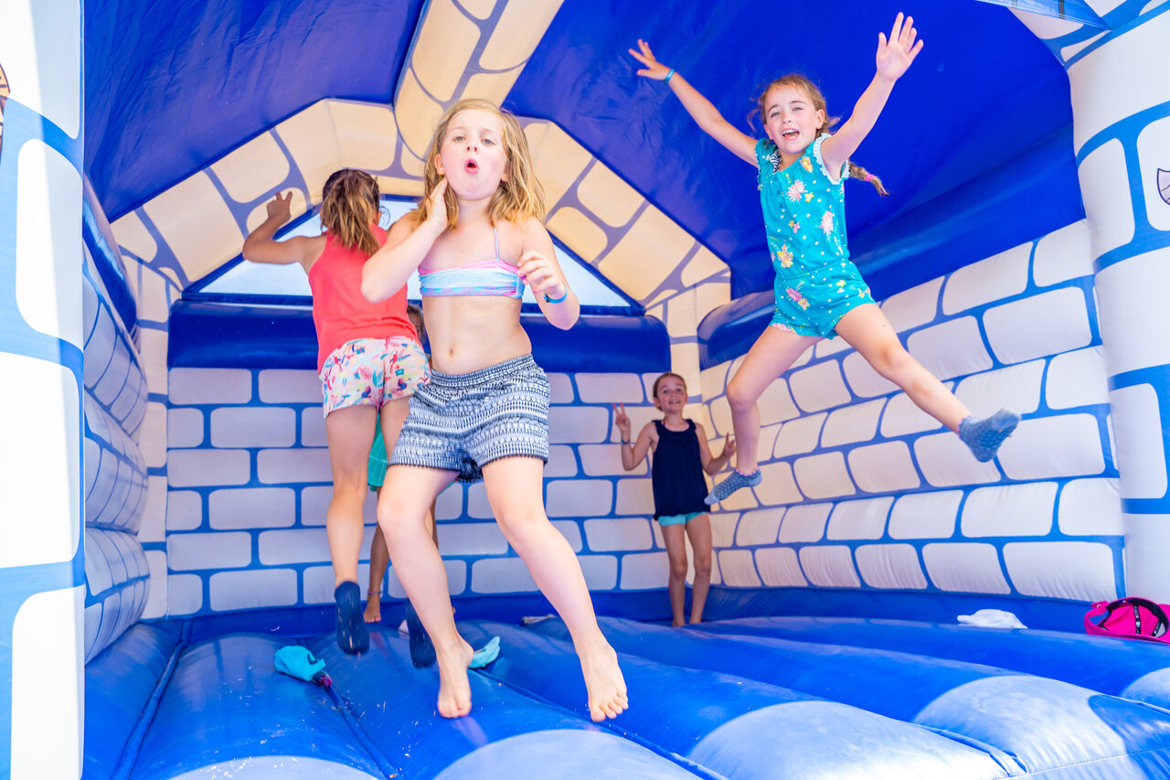 Enfants sautant joyeusement dans un ch�teau gonflable bleu au camping CAPFUN Palombi�re � Sarlat (24).