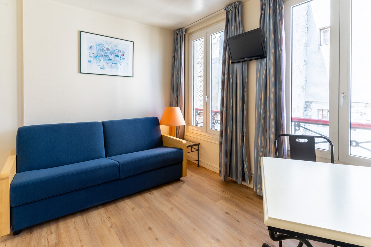 Canap�-lit, t�l�vision murale et coin repas dans h�bergement au camping CAPFUN Hotel Paris Saint Germain � PARIS (75).