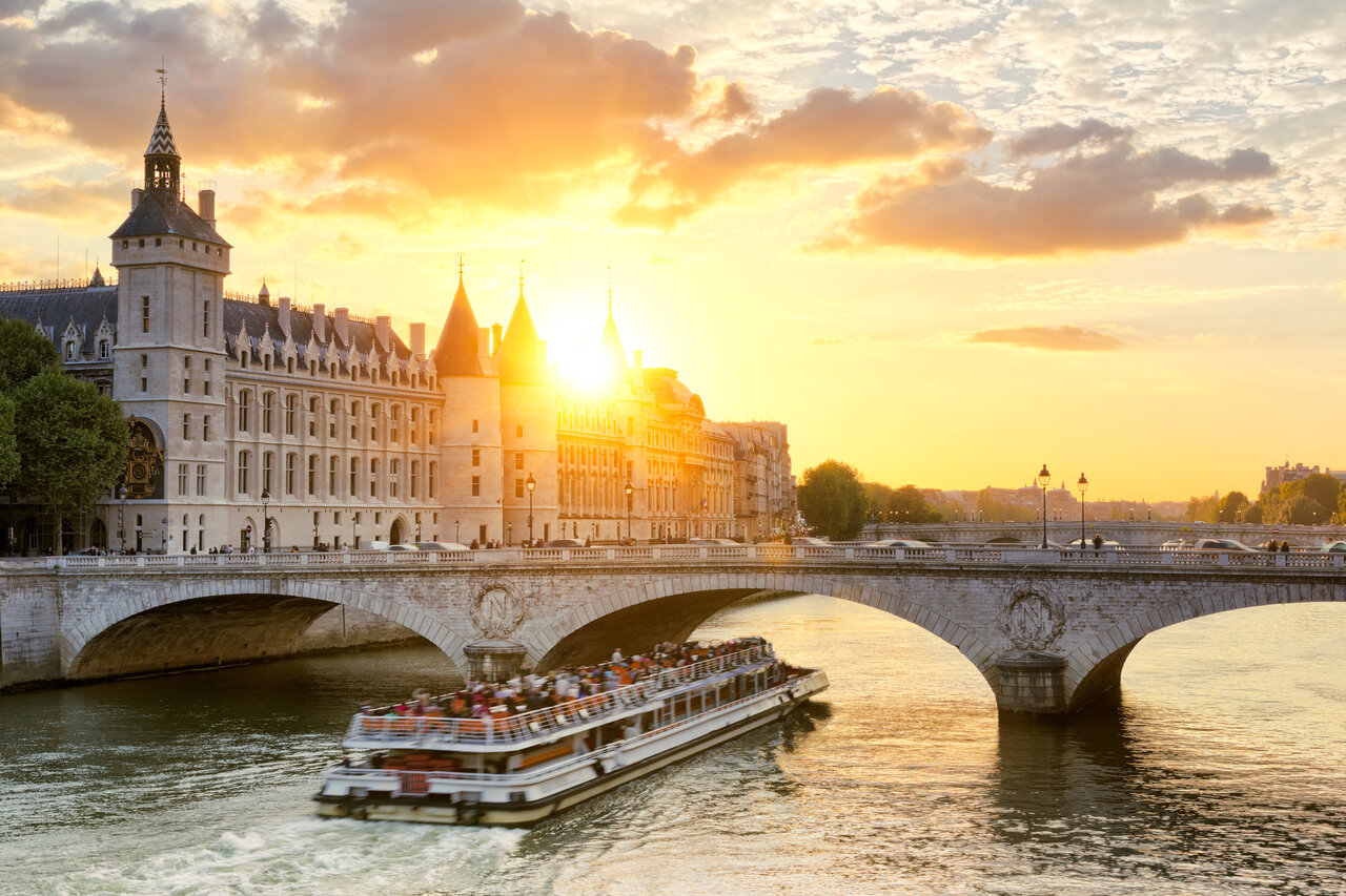 Bateau touristique sur la Seine, Conciergerie et Pont Neuf au coucher du soleil � Paris.