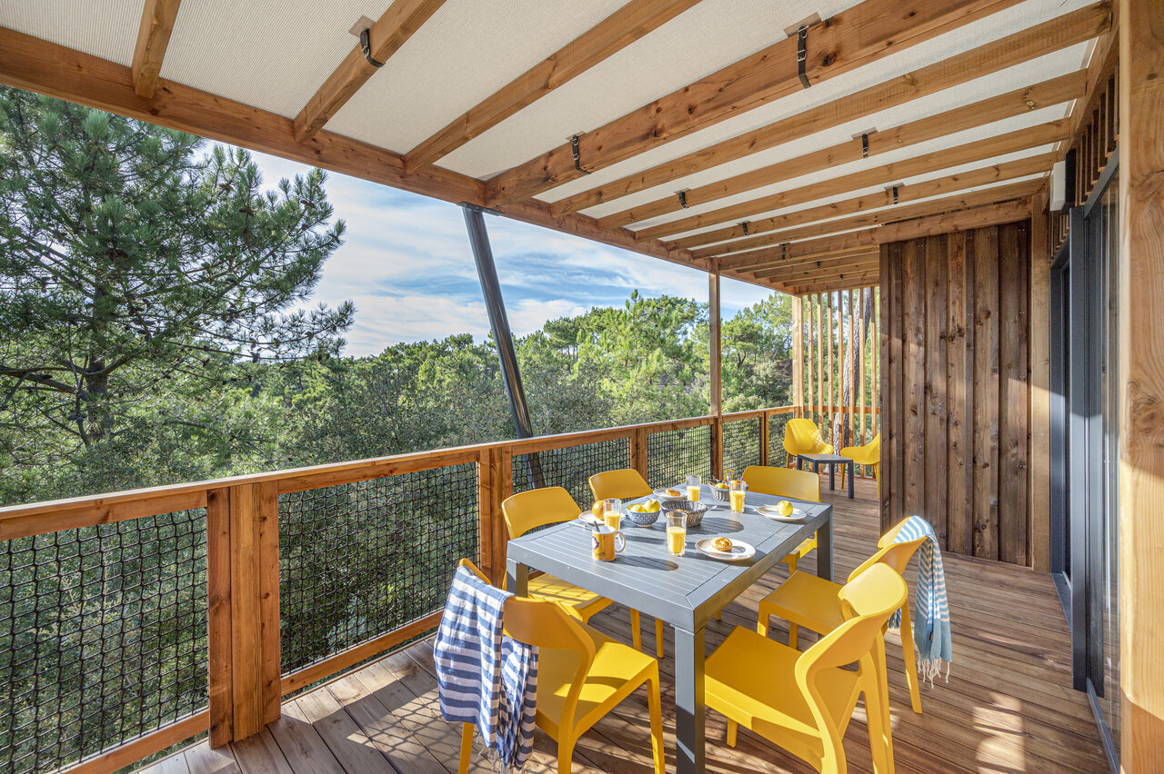 Terrasse de Mobil-home avec table et chaises jaunes, vue for�t au camping CLICOCHIC Petit Bec � St Hilaire de Riez (85).