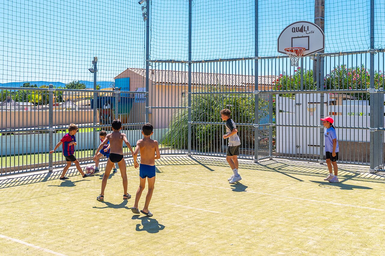 Enfants jouant au football et basketball sur terrain multisport au camping CAPFUN La Pin�de de Grimaud.