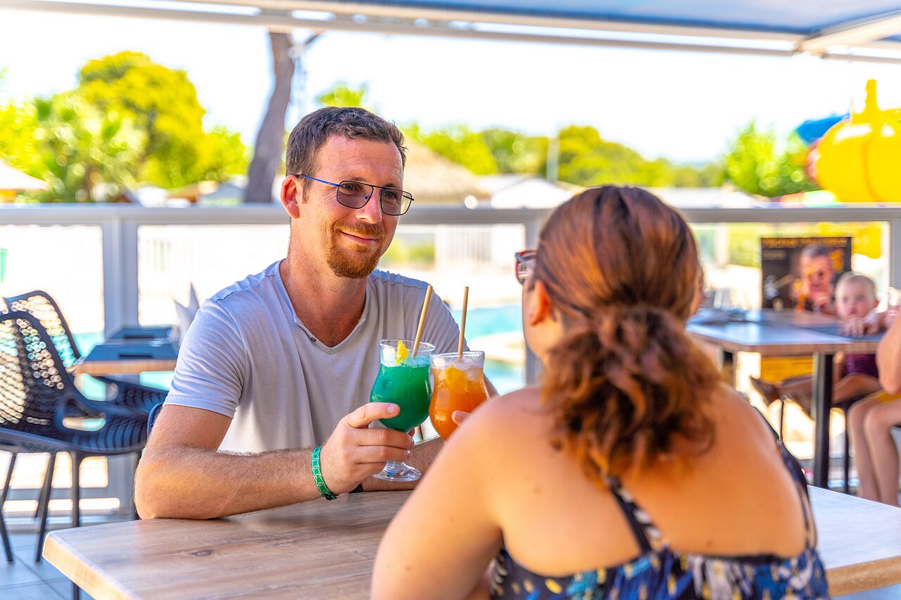 Couple souriant d�gustant des cocktails au bar du camping CAPFUN La Pin�de de Grimaud.