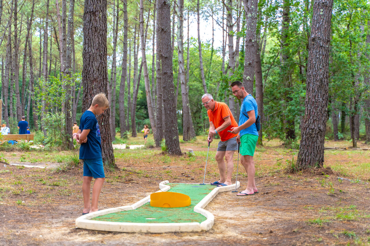Famille jouant au mini-golf en for�t au camping CAPFUN Pomme de Pin � Saubion (40).