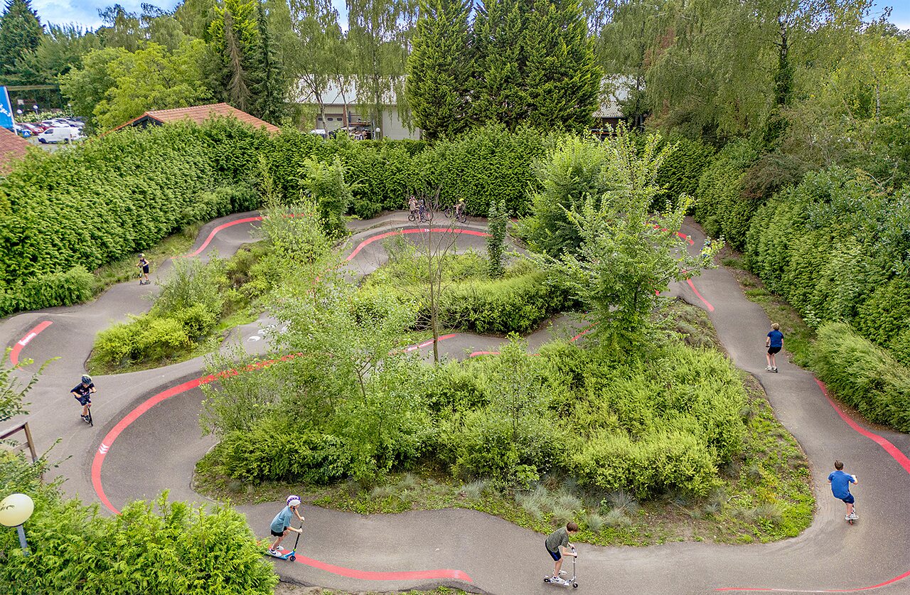 Enfants sur pumptrack avec trottinettes et v�los au camping CAPFUN Ponderosa � Ulicoten.