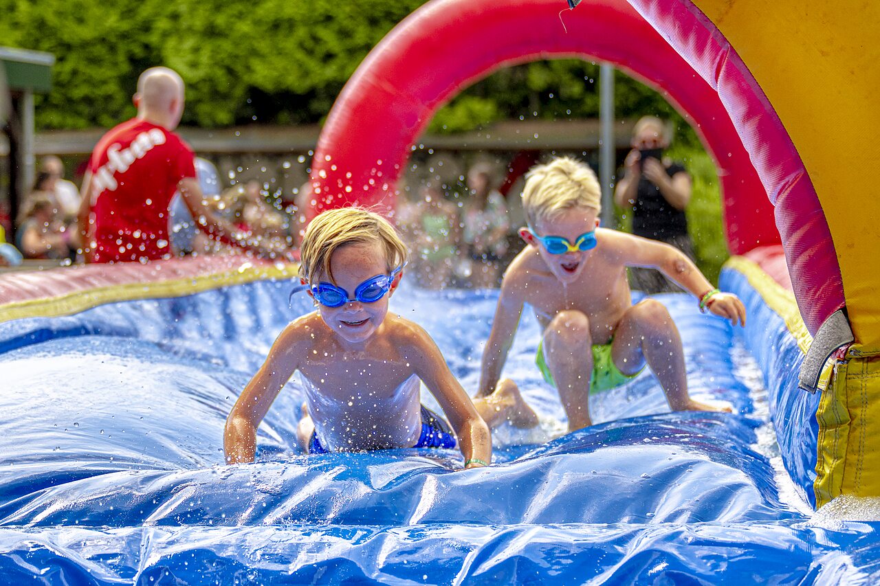 Enfants s'amusant sur toboggan aquatique gonflable au camping CAPFUN Ponderosa � Ulicoten.