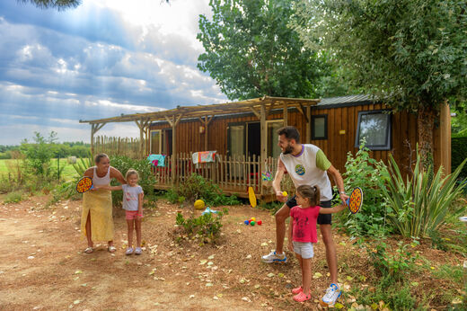 Famille jouant devant un Mobil-home avec terrasse au camping CAPFUN Prises à La TRANCHE SUR MER (85).