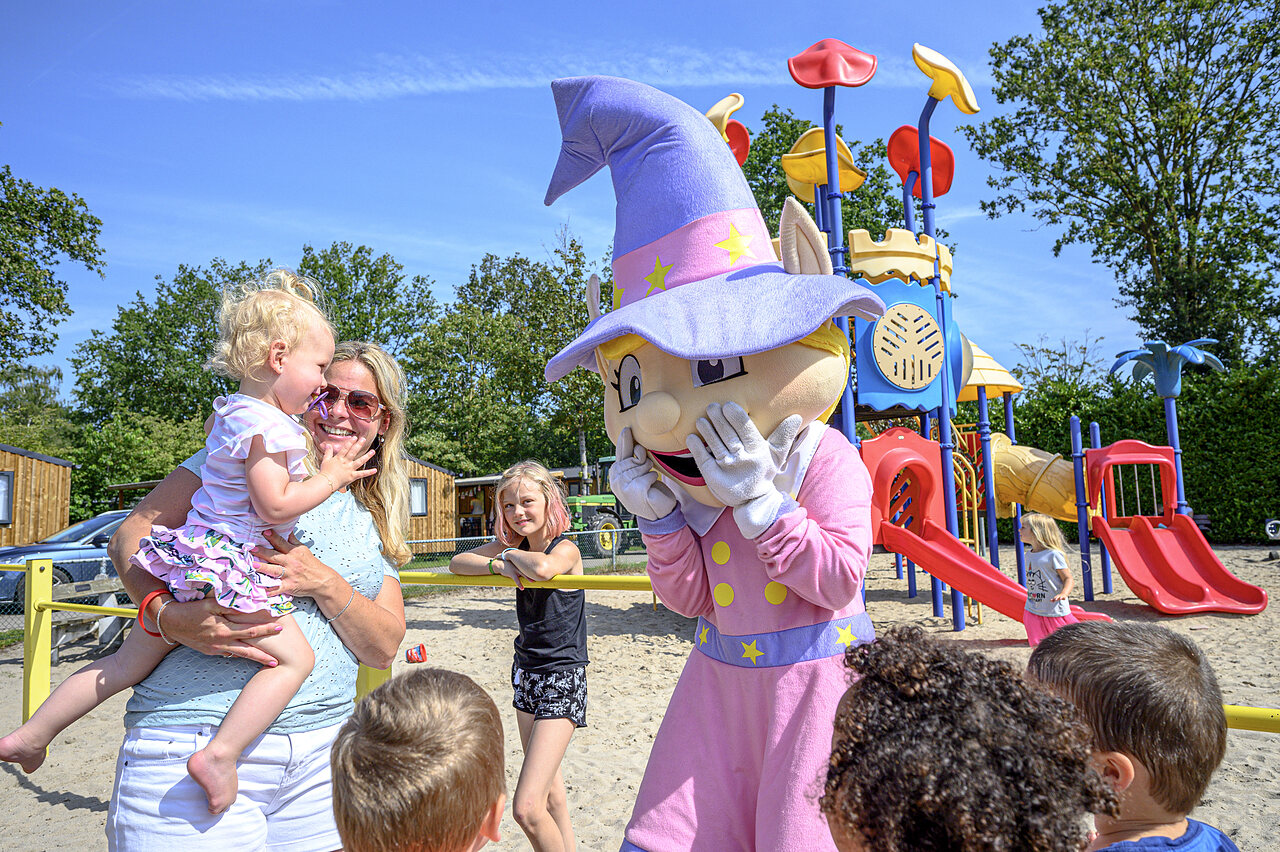 Mascotte et enfants souriants sur l'aire de jeux du camping CAPFUN Rakelbos � Westelbeers.