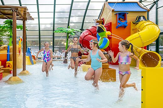Aire de jeux aquatique couverte avec toboggans et enfants au camping CAPFUN Rakelbos à Westelbeers.