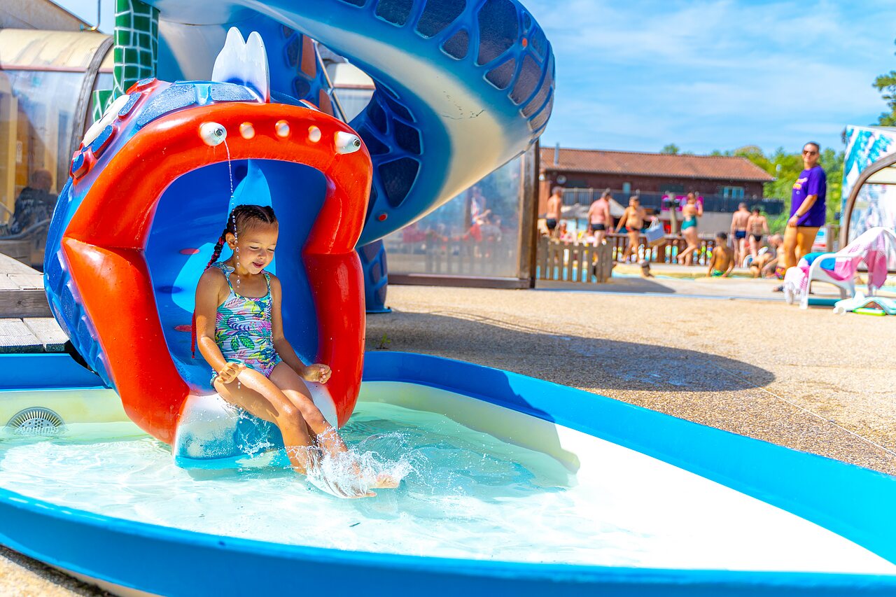 Fille glissant sur toboggan aquatique color� dans la pataugeoire au camping CAPFUN R�gni�re � VILLETTE D'ANTHON (38).