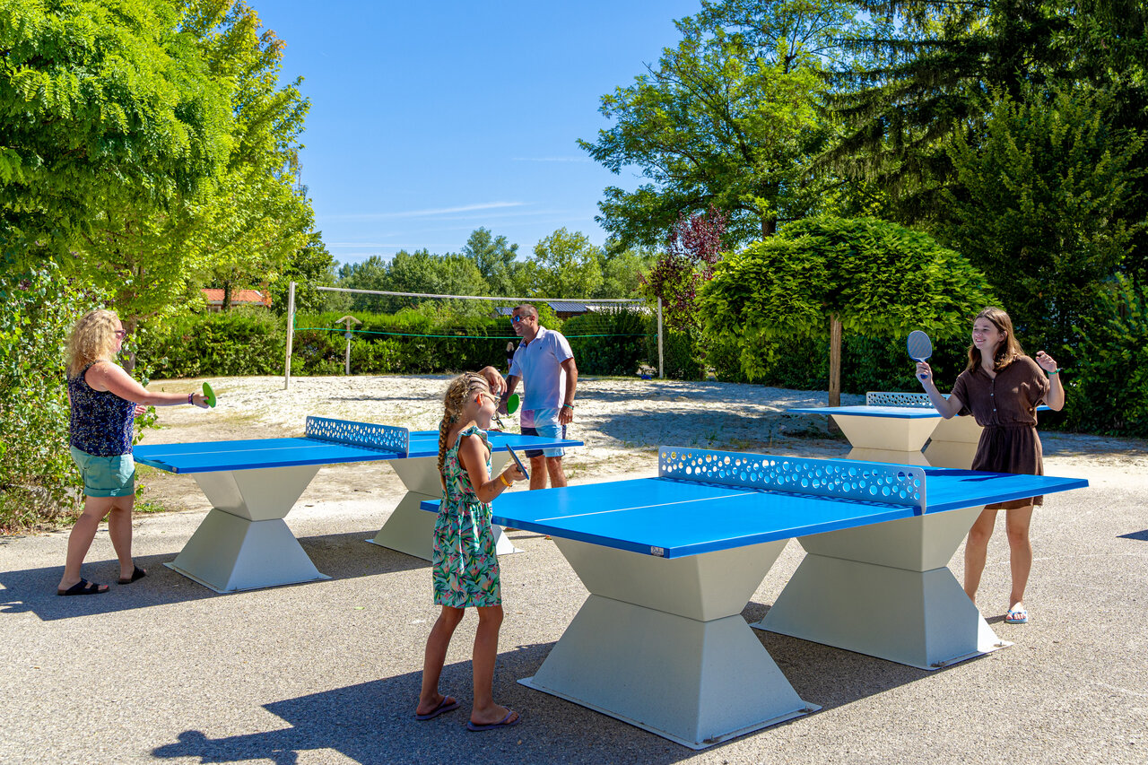 Famille jouant ping-pong sur tables ext�rieures au camping CAPFUN R�gni�re : Maisons dans les arbres � Lyon � Villette d'Anthon (38).