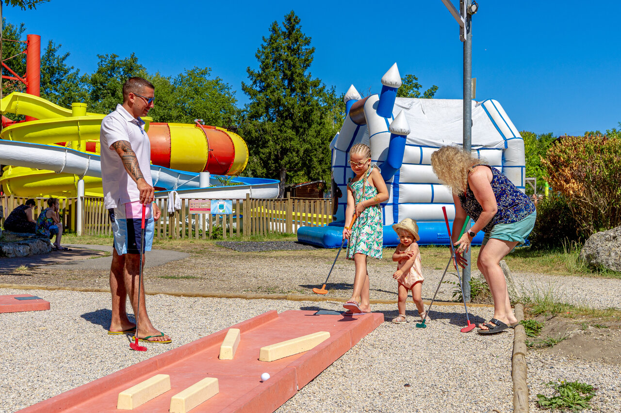Famille jouant au mini-golf avec toboggans aquatiques au camping CAPFUN R�gni�re � Villette d'Anthon.